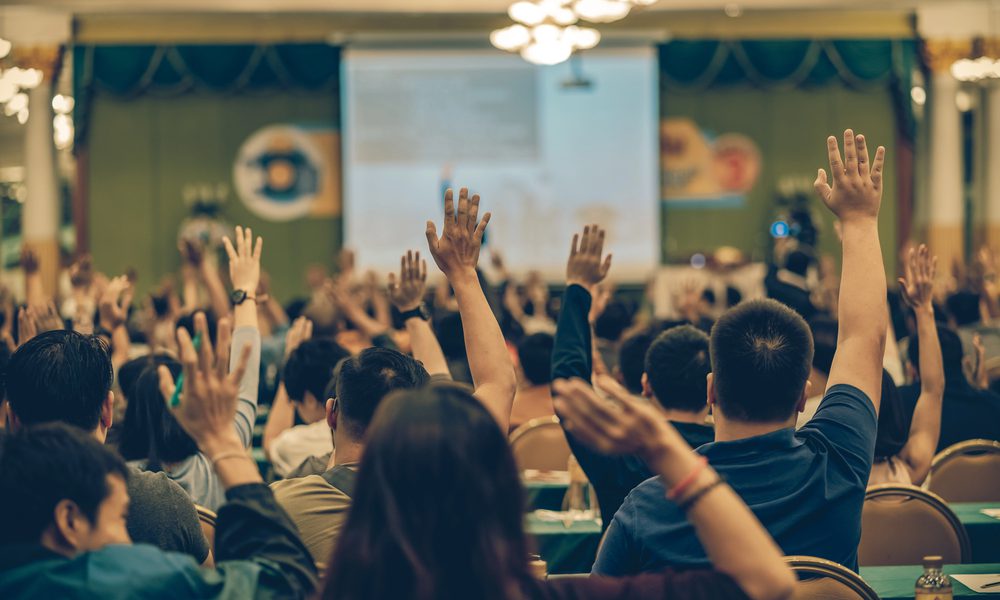 A group of attendees raising their hands at an event.