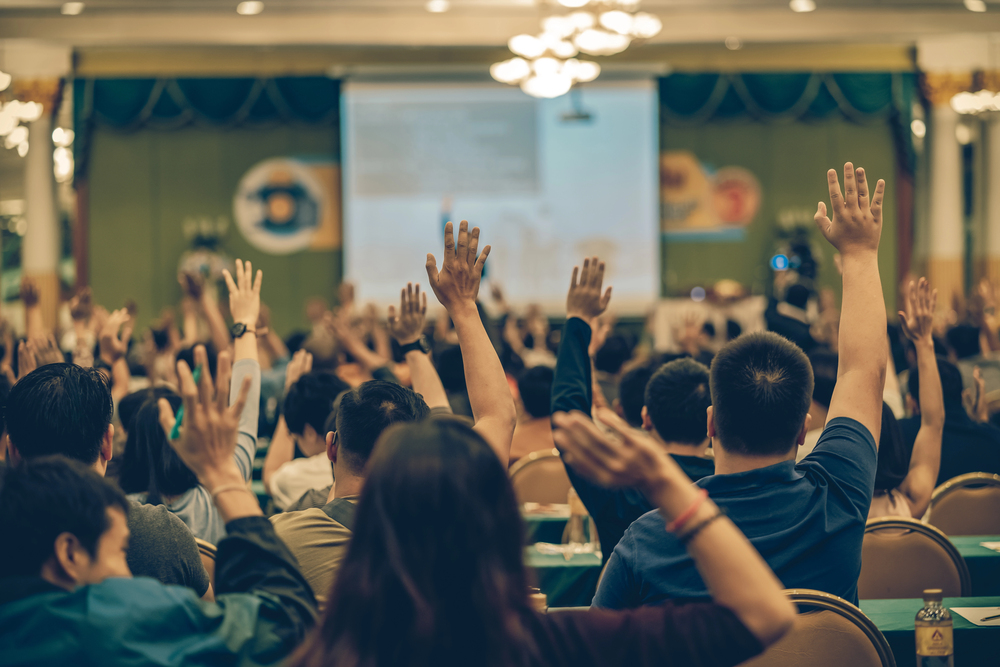 A group of attendees raising their hands at an event.